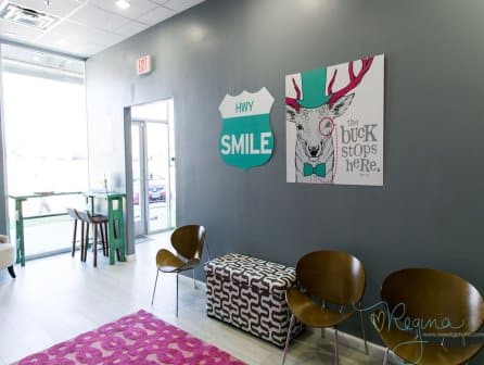 Route 32 Dental kids play room seating area view of wall decoration with animated character an office sign: Smile HWY and The buck stops here