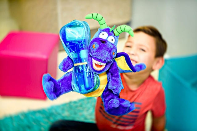 A happy smiling young patient showing off his special promotion gift package bundled with a happy smiling dragon toy