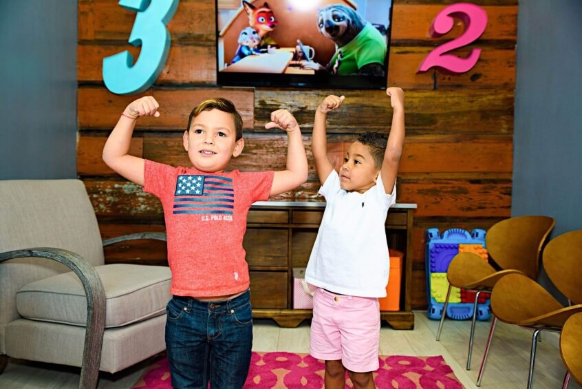 Two young patient boys flexing their hero muscles in the kids play area in Route 32 Dental office